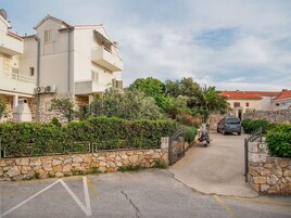 Una calle residencial con muros de piedra, una motocicleta estacionada y un automóvil.