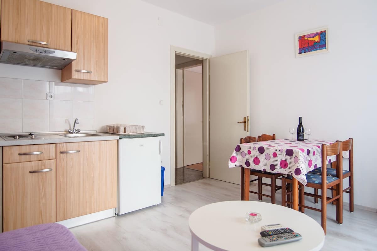 A compact kitchen with wooden cabinets, a built-in oven, and a dining area with a table set for two.