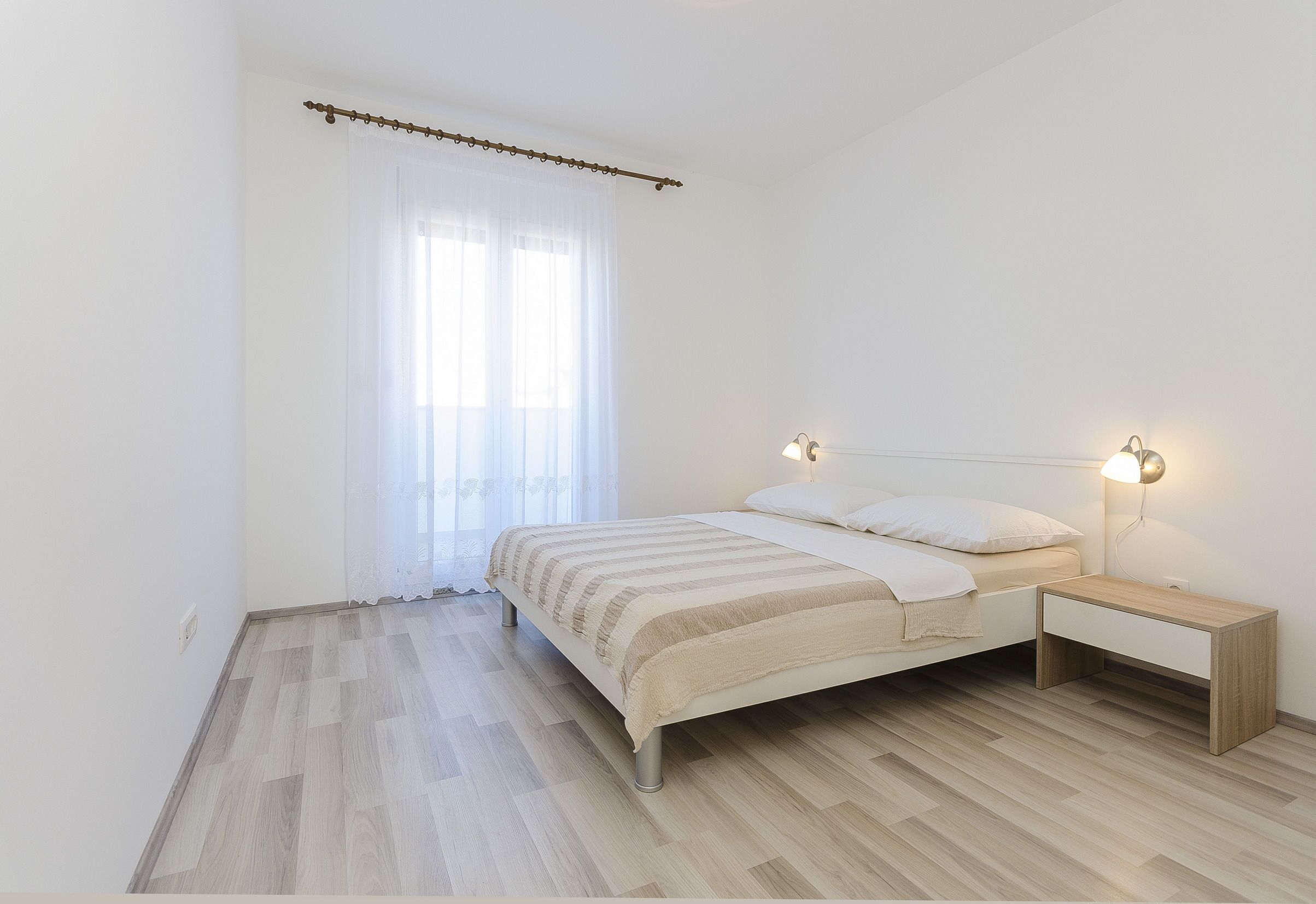 A bedroom with a bed, bedside table, and a window with curtains.