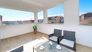 Ein Balkon mit Korbmöbeln, einem Tisch mit Tassen und einem Blumentopf.