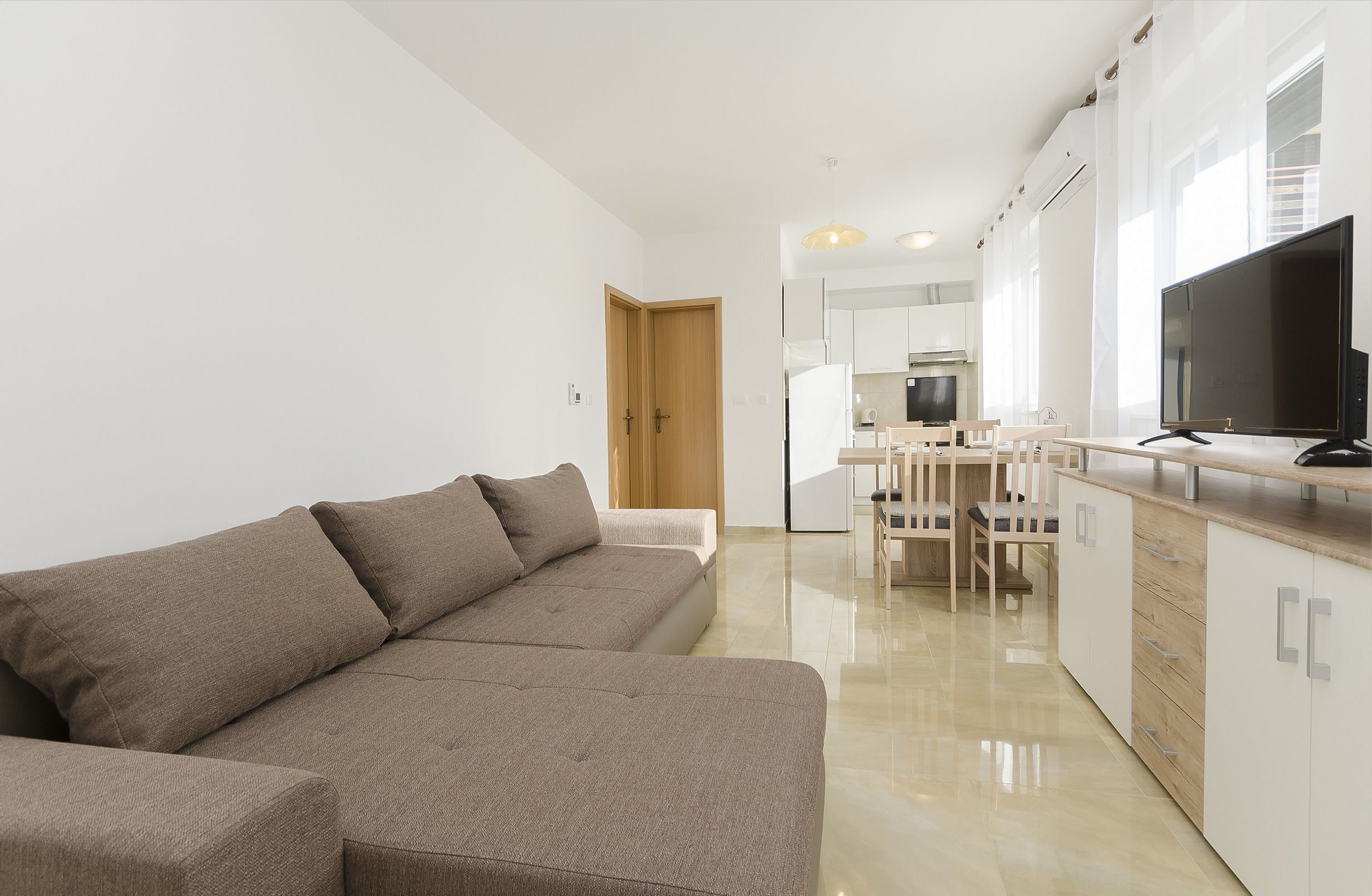 En moderne lejlighed med en opholdsstue med sofa og et spiseområde med bord og stole.