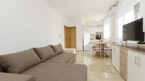 Eine moderne Wohnung mit Wohnbereich, inklusive Sofa, sowie Essbereich mit Tisch und Stühlen.