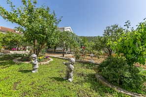 En have med to stenhager af børn, omgivet af frodig vegetation og blomstrende planter.