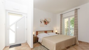 A bedroom with a bed, bedside tables, a door, and a window. - Apartments Karolina (Vodice)
