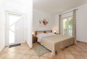 Un dormitorio con cama, mesitas de noche, una puerta y una ventana.