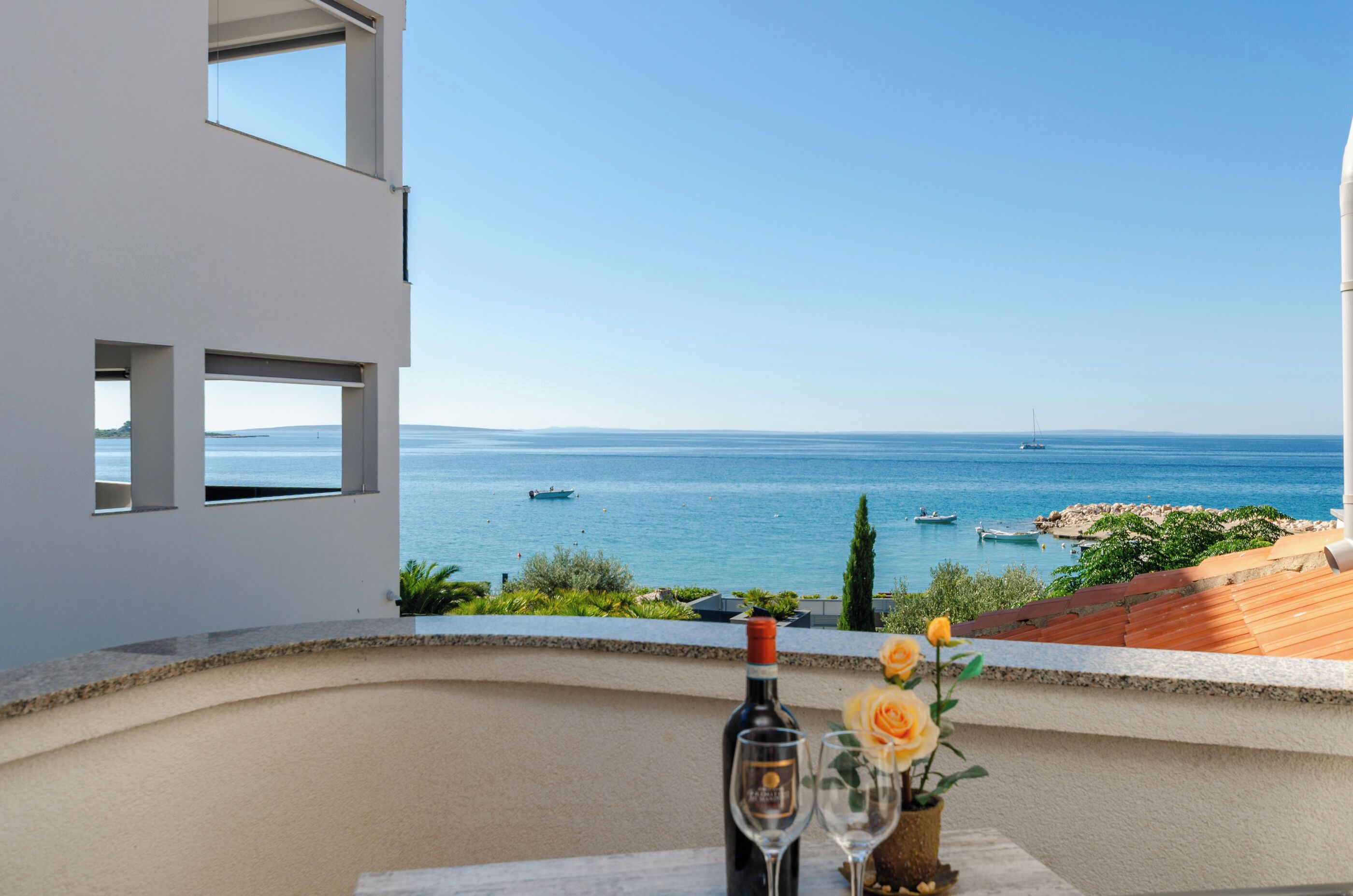 Un balcón con vista despejada al mar, una botella de vino y una copa.
