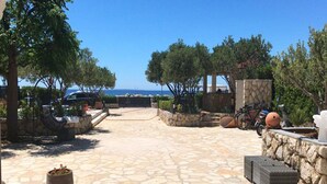 Eine terrasse mit Steinpflasterung, Sitzgelegenheiten im Freien, einer Steinmauer und Blick aufs Meer.
