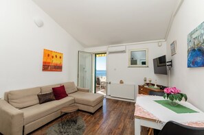 A living room with a sofa, a table with a vase of flowers, and a painting on the wall. - Apartments Daniela Della (Novalja)