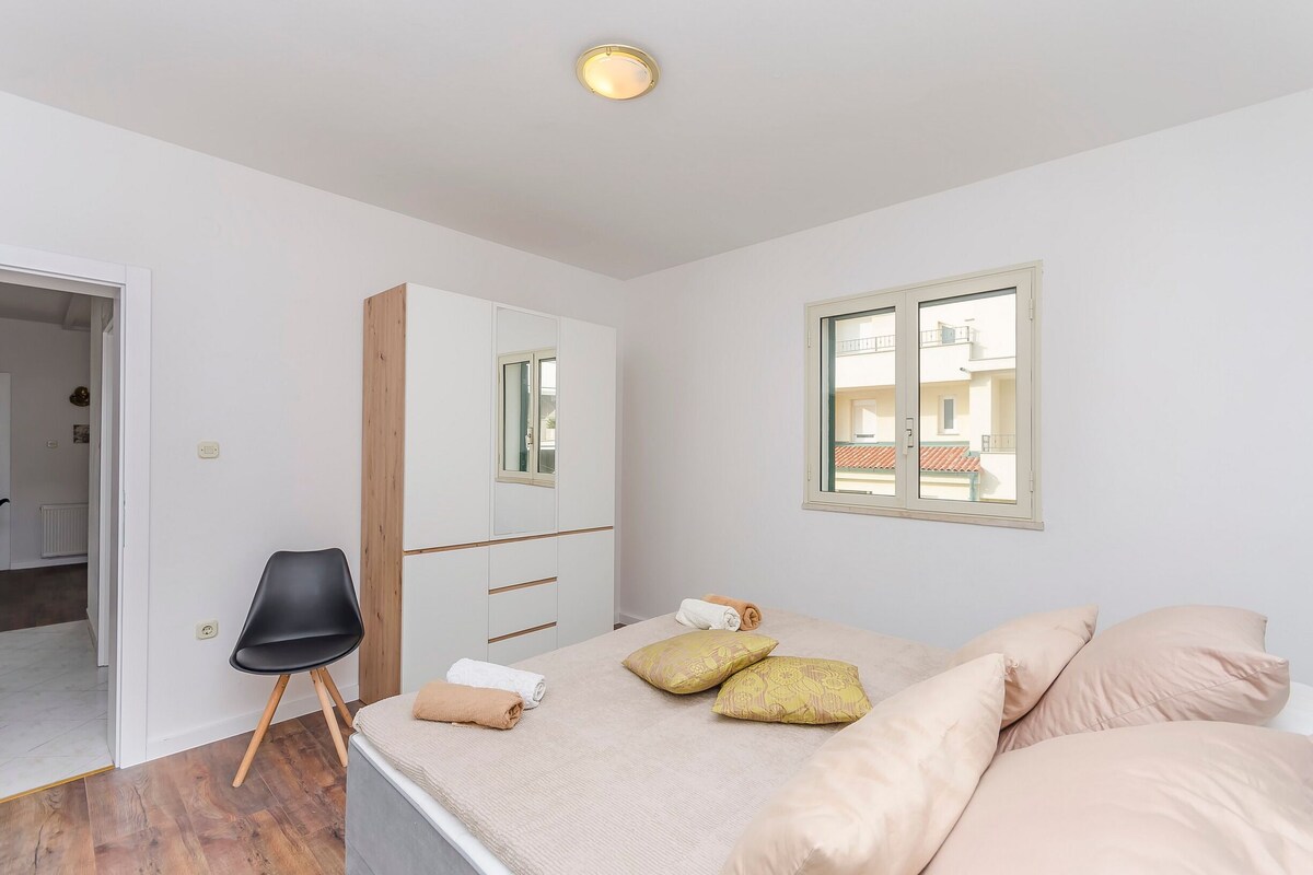 A bedroom with a bed, a chair, a wardrobe, and a window.