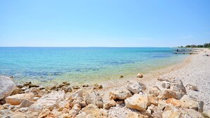 Ein felsiger Strand mit klarem Wasser und einer entfernten Küstenlinie.