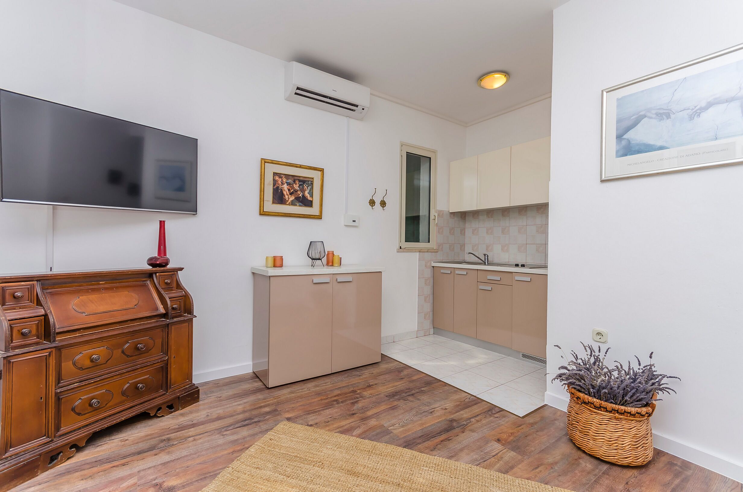 A modern kitchen with wooden cabinets, a built-in oven, and a flat-screen TV mounted on the wall.