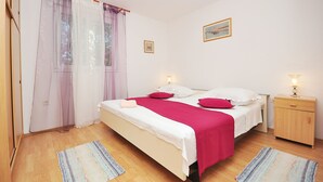 Ein Schlafzimmer mit einem Bett, Nachttischen und einem Fenster mit durchsichtigen Vorhängen.