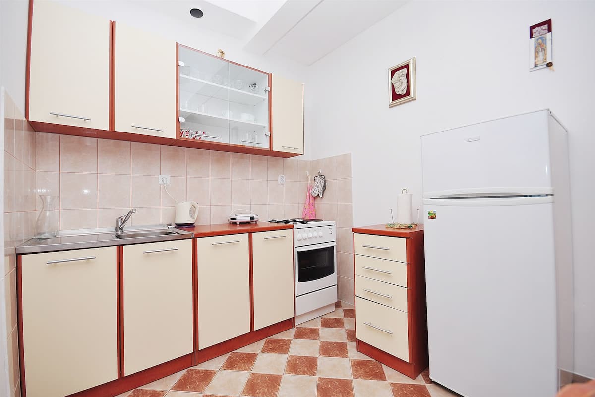 A kitchen with beige cabinets, a white refrigerator, a stove, and a sink.