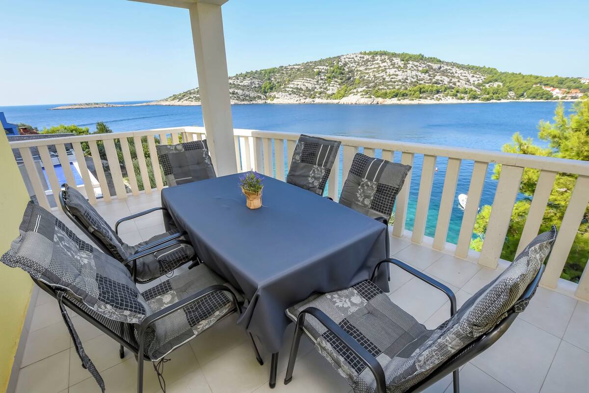 Una terrazza con tavolo e sedie, affacciata sulla costa.