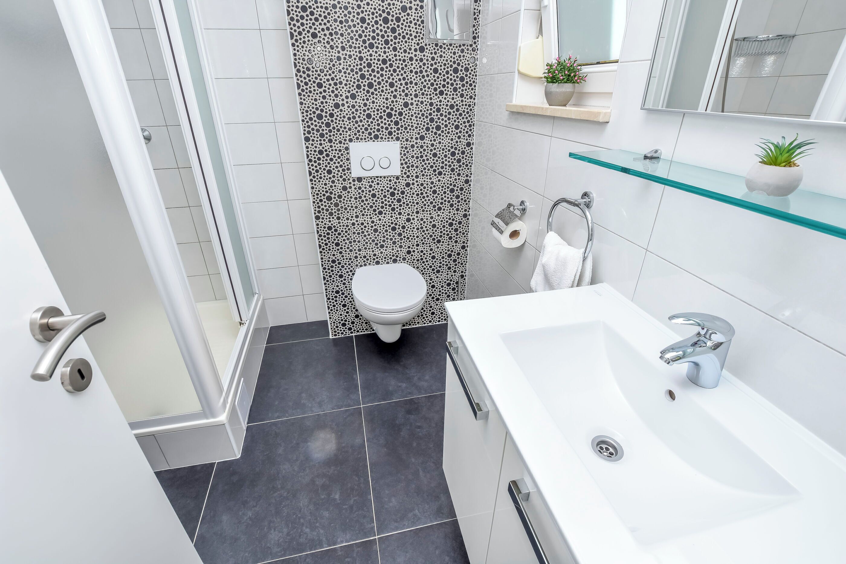 A modern bathroom with a shower, toilet, and sink.