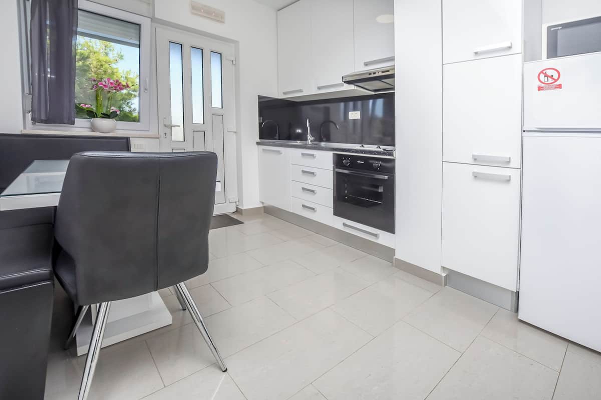 Una cucina moderna con mobili bianchi, un piano di lavoro nero e elettrodomestici in acciaio inossidabile.