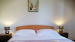 A neatly made bed with white linens, two rolled towels on the bed, and two bedside lamps on nightstands. - Apartments and Room Caric (Jelsa)
