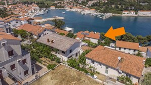A coastal town with terracotta-roofed buildings, a marina, and a prominent church spire. - Apartments and Room Caric (Jelsa)