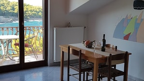 A dining area with a table and chairs, a radiator, and a view of the sea through a glass door. - Apartments and Room Caric (Jelsa)