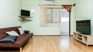 A living room with a brown leather sofa, a TV on a wooden stand, and a large window with a curtain. - House Ivana Tribunj (Tribunj)
