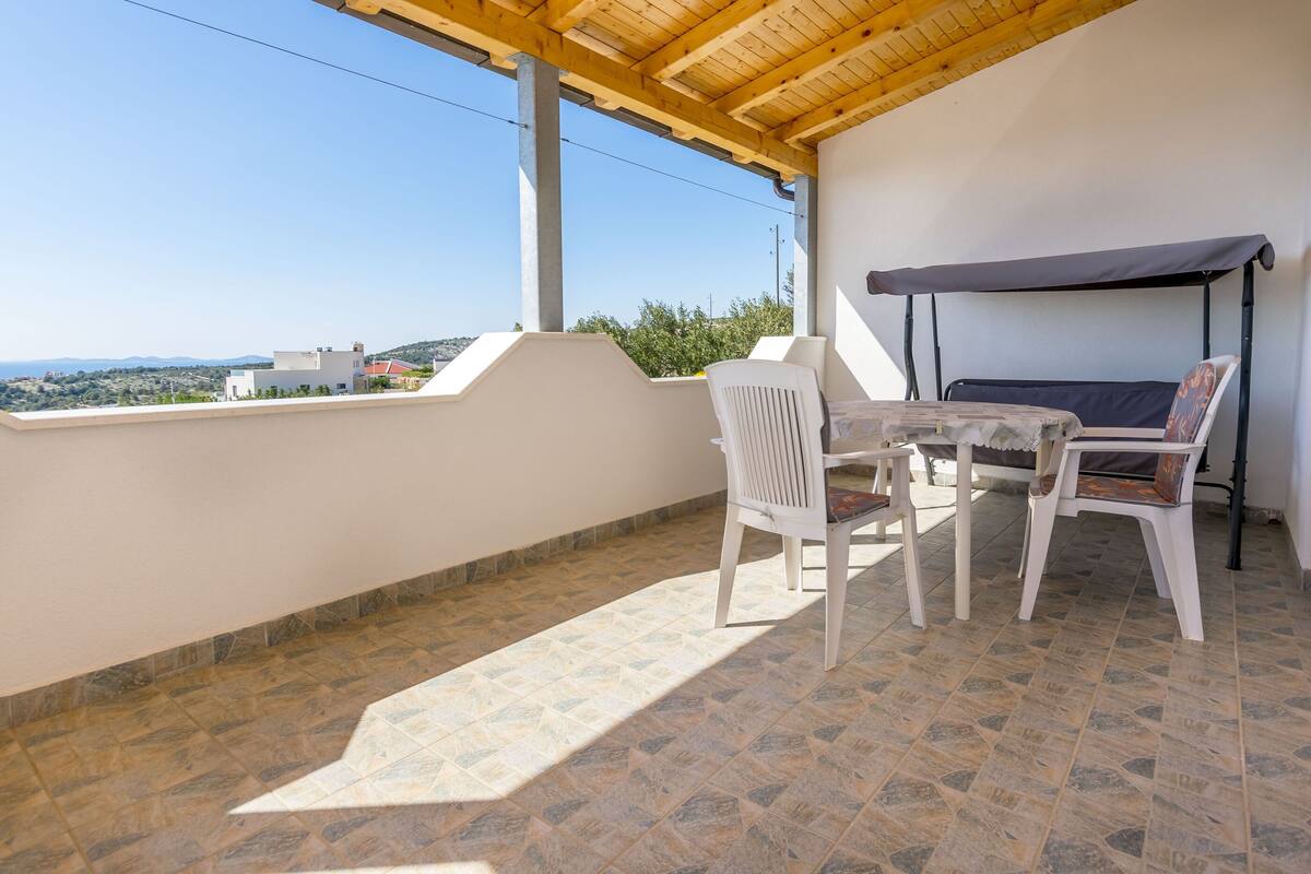 A balcony with a table and chairs, a covered seating area, and a view of the landscape.