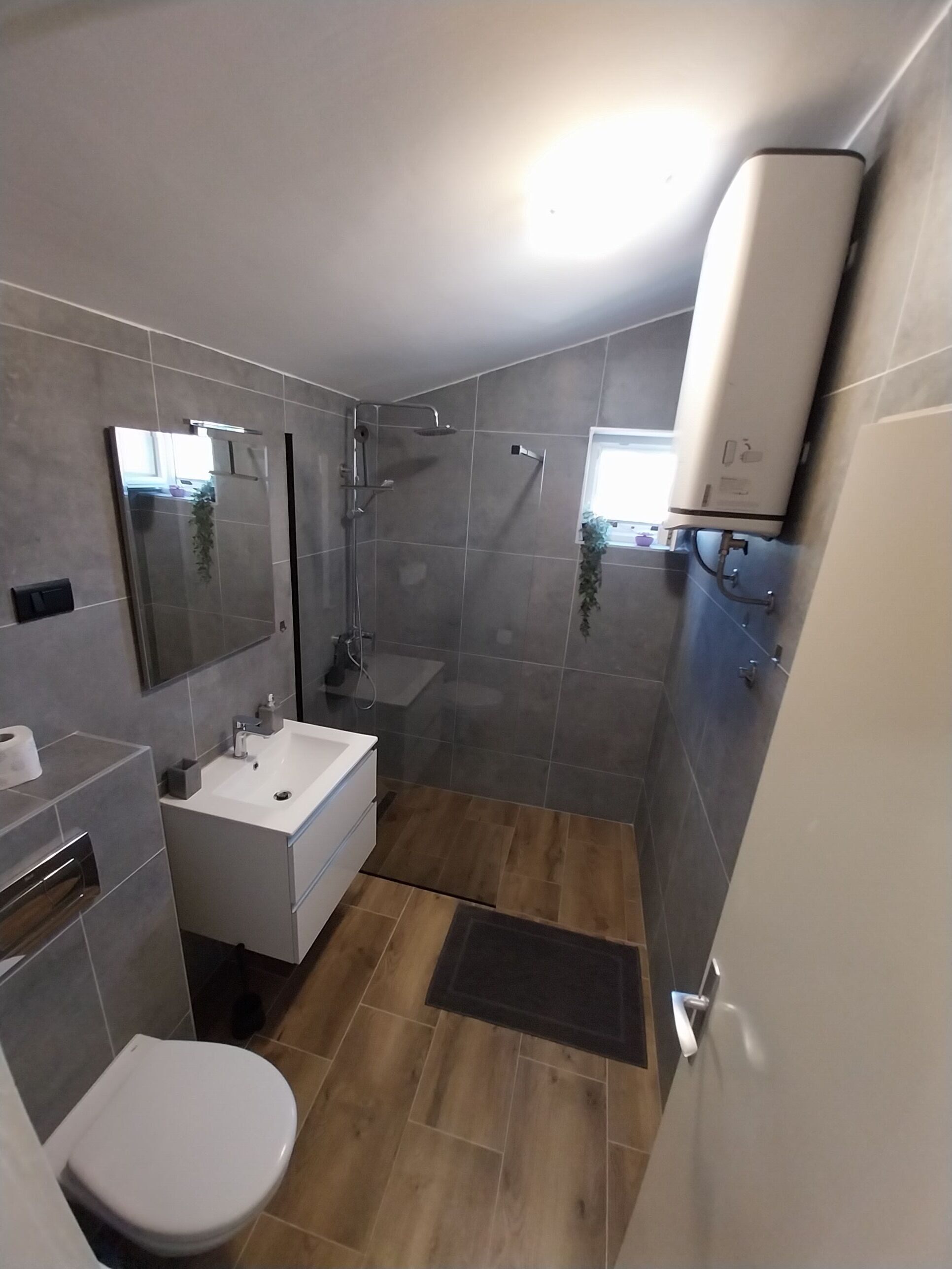 A modern bathroom with a shower, toilet, and sink.