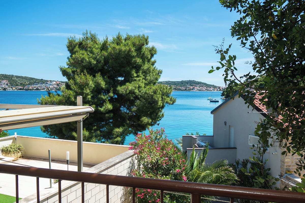 A balcony with a view of the sea and a tree.