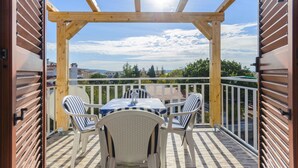 Un patio techado al aire libre con una mesa y sillas, una pérgola de madera y vistas del paisaje circundante.