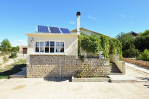 Et hus med stenvægge, skorsten og solpaneler.
