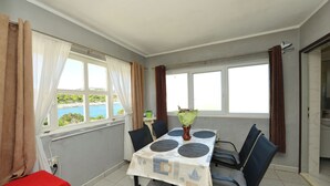 Un espace repas comprenant une table, des chaises et une vue sur la mer.