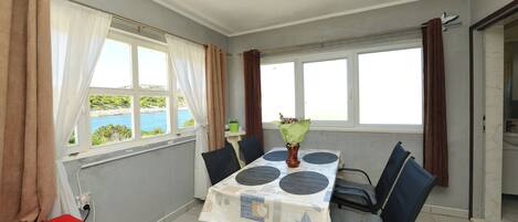A dining area with a table, chairs, and a view of the sea.