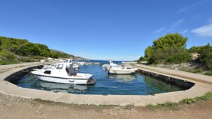 Un port de plaisance où des bateaux sont amarrés dans un bassin en béton, entouré de verdure et sous un ciel dégagé.