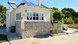Une maison dotée de panneaux solaires, d’une cheminée et d’un mur en pierre.