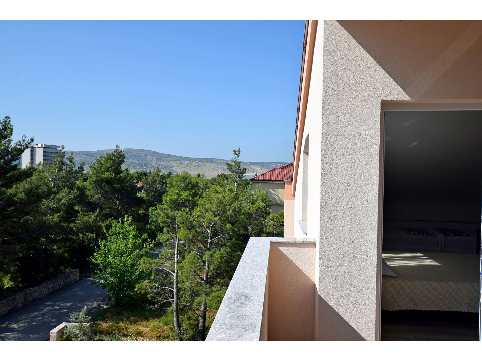 A balcony with a view of a mountain, trees, and a road.