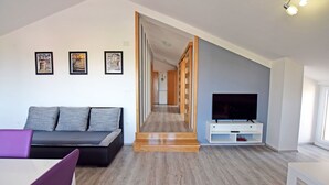 A modern living room with a sofa, a TV, and framed pictures on the wall. - Apartments Branka (Starigrad - Paklenica)