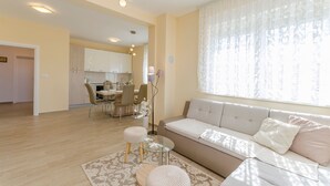 A modern living room with a sofa, ottomans, and a glass coffee table. - Apartments Luxury and Sea View (Brodarica)