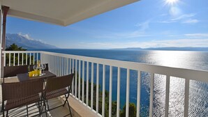 A balcony with a table set for two, overlooking a body of water and distant mountains. - Apartments Danolic (Pisak)