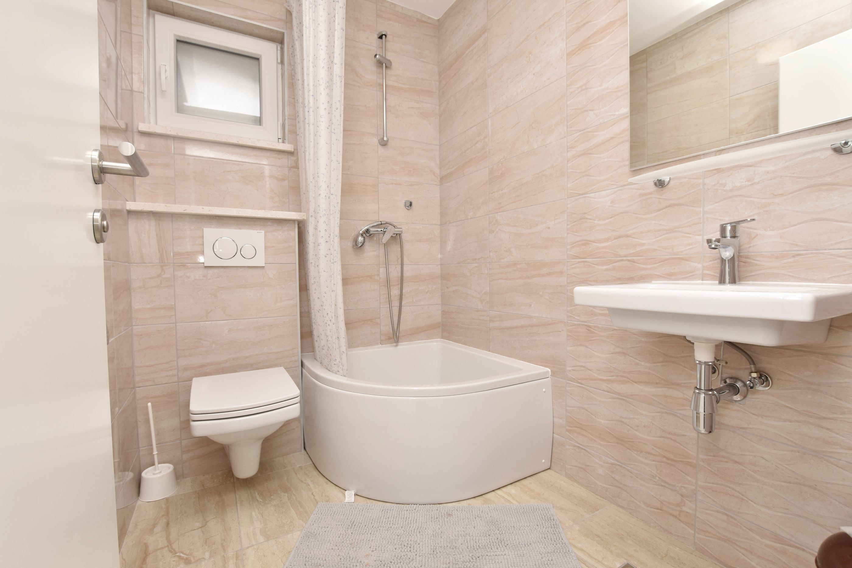 Een moderne badkamer met een hoekbad, toilet, wastafel en douche.