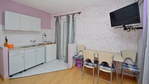Una cucina compatta con mobili bianchi, un lavello e una zona pranzo con tavolo e sedie.