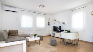 A modern living room with a sofa, coffee table, TV, and dining area. - House Goran (Kolan)