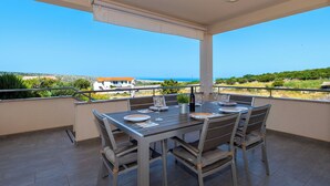 A balcony with a table set for two, overlooking a scenic view of the sea and buildings. - House Goran (Kolan)