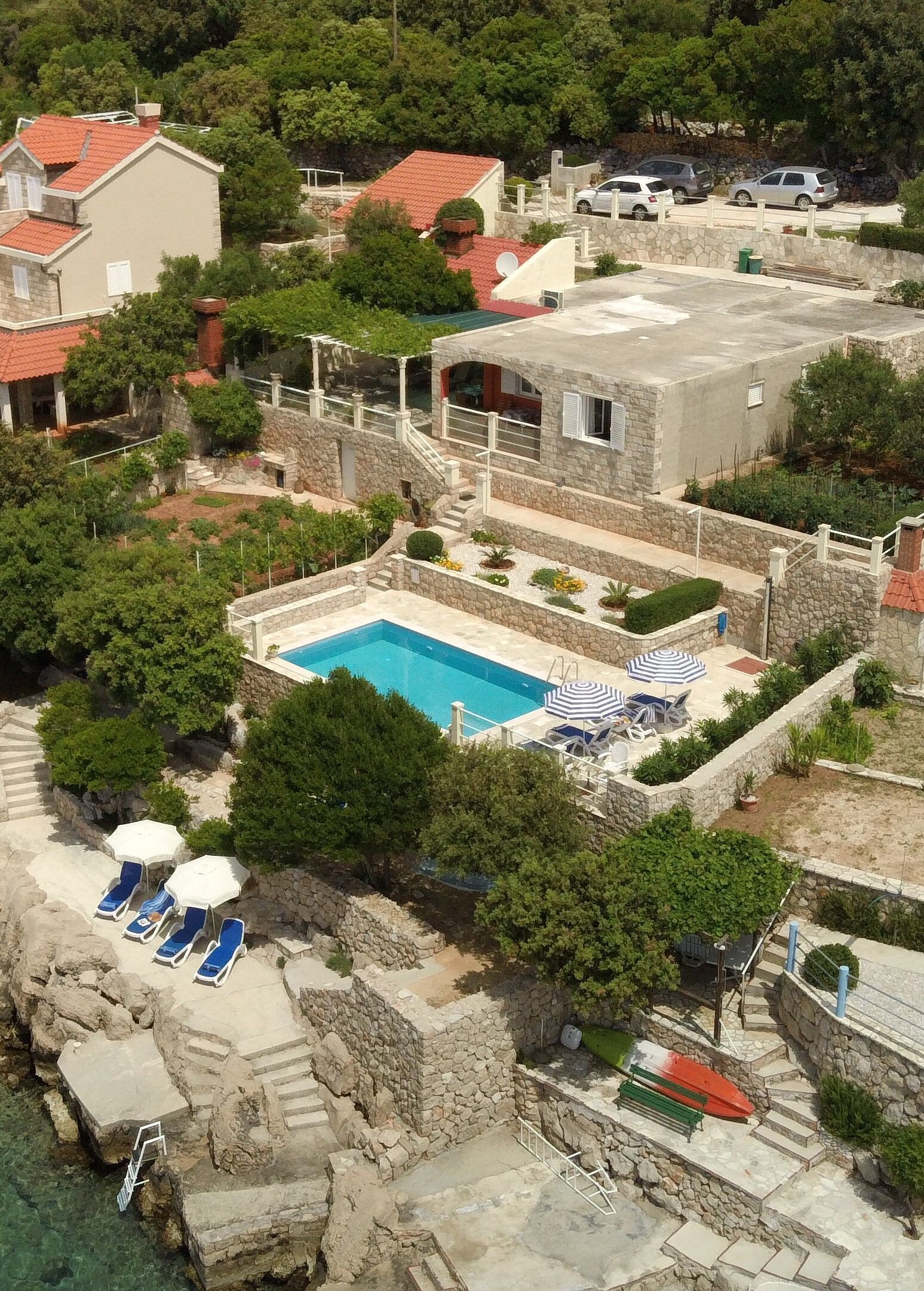 A residential area with a swimming pool, lounge chairs, and umbrellas.