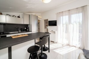 Een moderne keuken met een centraal eiland, barstoelen, een flatscreen televisie en een zithoek met een bank.