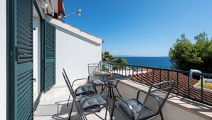 A balcony with a table and chairs, a view of the sea, and a railing. - Apartments Villa Bok (Okrug Gornji)