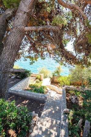 A stone pathway leading to a seating area with a view of the sea. - Apartments Villa Bok (Okrug Gornji)
