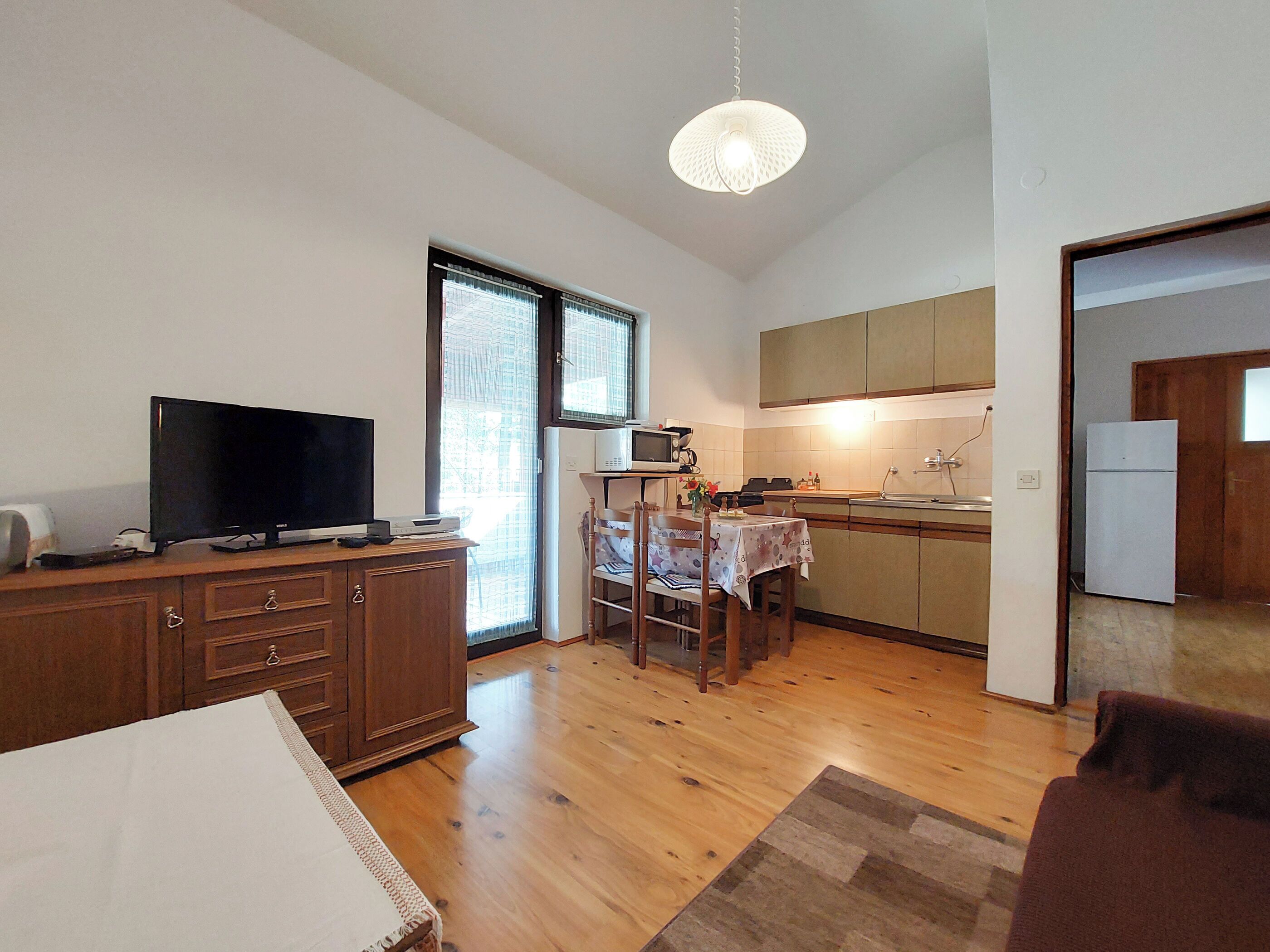A compact kitchen with a dining area, a television, and a refrigerator.