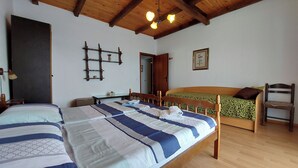 Ein Zimmer mit zwei Betten, Holzbalken an der Decke, einem kleinen Tisch und einem Stuhl.