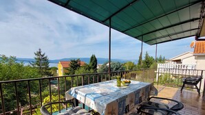 Ein Balkon mit Tisch für zwei Personen, mit Blick auf eine malerische Seen- und Berglandschaft.