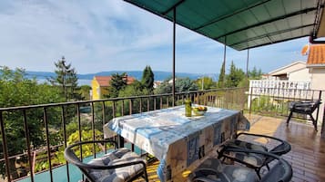 Varanda com uma mesa posta para dois, com vista panorâmica para um lago e montanhas.