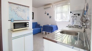 Eine kleine Küche mit Mikrowelle, Spüle und einer Karte an der Wand.